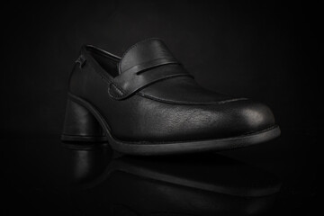 Close up of stylish female shoe. Black leather casual women's shoe on black background