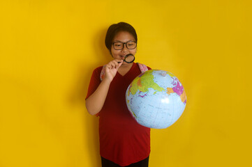 Asian little girl student wear glasses, looking at globe through magnifying glass isolated on...