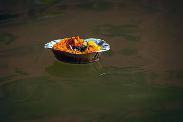 Isolated image of a floating lamp with flowers and candle offered to holy river Ganges at Varanasi...
