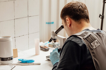 The inseminator examines animal sperm with a microscope and a thermostat for defrosting sperm,...