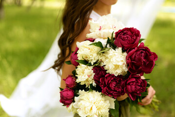 a girl holding a bouquet of peonies in the park, the flowers are pink and white