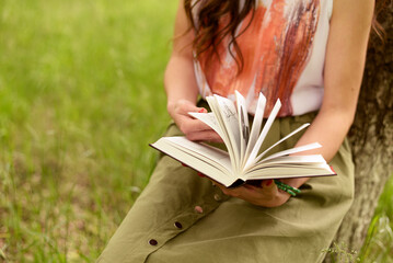 woman in the green grass reading a book