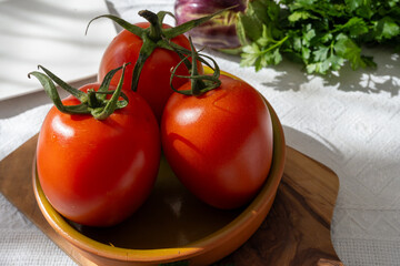 Ripe red Roma tomatoes in bowl with fresh herbs