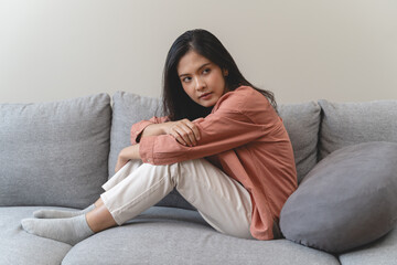 Stressed female feeling depressed and lonely on the sofa in the house. - obrazy, fototapety, plakaty