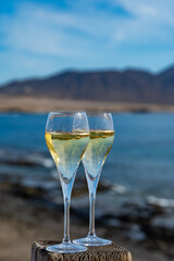 Pouring a glass of champagne on vacation, south of Fuerteventura, Canary islands, blue ocean, mountains