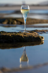 A glass of champagne or cava on vacation, low tide on Dunes Corralejo sandy beach, Fuerteventura,...