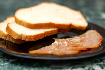 Food ingredients like slices of meat and bread served on black plate