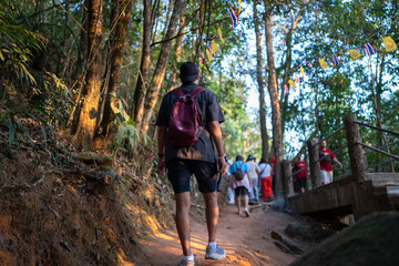 Asian tourists are walking up Khao Khitchakut, through large trees in the forest, tourist attraction Chanthaburi, Thailand.