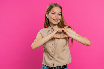 Woman in love. Smiling attractive woman makes heart gesture demonstrates love sign expresses good...