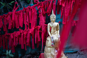 Golden Buddha statue and red cloth at Buddha's footprint and giant rocks at Khao Khitchakut National Park, Chanthaburi, Thailand.