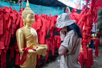 Women worshiping the golden Buddha statue and red cloth at Buddha's footprint and giant rocks at...