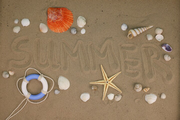 The word summer is written with a finger in the sand. around the word lie shells, a lifebuoy and a starfish