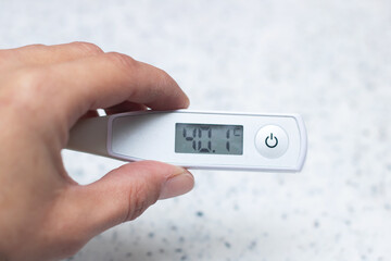 Temperature of 40.1 shown on digital thermometer held by hand