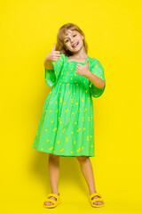 Like. Happy preteen child girl kid looking approvingly at camera showing thumbs up, like sign positive something good, positive feedback great news. Children isolated on yellow background. Vertical