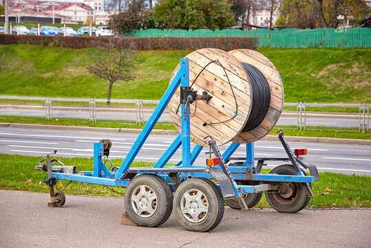 Trailer with mounted wooden coil with fiber optic cable. Laying optical fiber cable in the city, high speed internet and communications. Cabling,  underground communications
