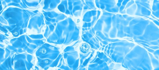 Realistic blue water wave texture background with ripples, splash and bubbles. Blue water surface with reflection of sunlight. Minimal summer concept. Top view, copy space