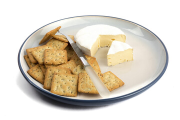 a plate of multigrain crackers with a round of brie cheese isolated on white