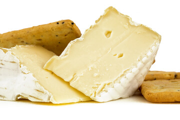 extreme closeup of two wedges of brie cheese with multigrain crackers isolated on white