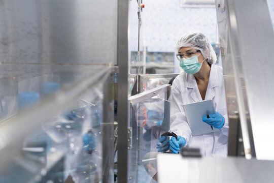 Female worker produces inspecting quality of plastic water tank on conveyor belt in drinking water factory. Worker using tablet working and checking bottle or gallon on conveyor production line