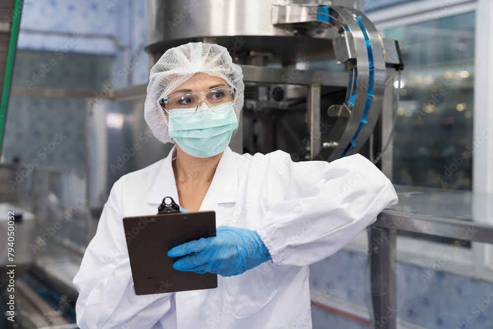 Wall mural female worker produces inspecting quality of plastic water tank on conveyor belt in drinking water f