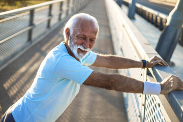Portrait of sporty senior man outdoors. Handsome jogger doing stretching
