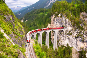 Swiss red train on viaduct in mountain, scenic ride - 794059249