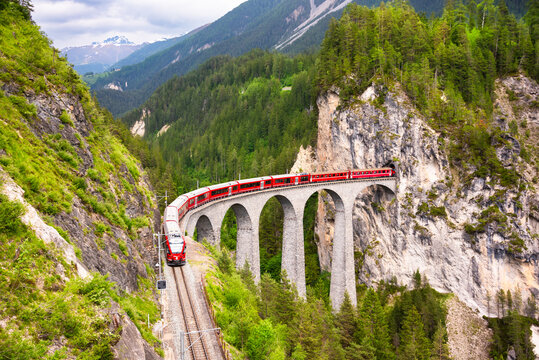 Swiss red train on viaduct in mountain, scenic ride