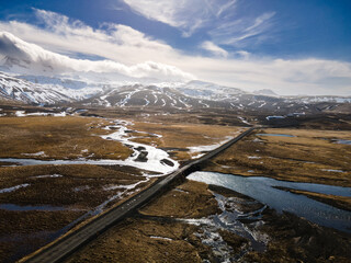 dirt road across Icelandic highlands with a river crossing and mountains in the clouds at the...