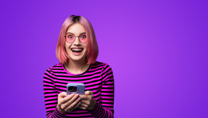 Excited surprised shocked astonished very happy pink woman wear braces sunglasses eye glass spectacles open mouth hold typing cell phone cellular smartphone cellphone isolated over purple background.
