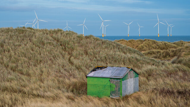 Offshore Wind Turbines at Redcar, north-east England, set against Coatham dunes and a fisherman's cabin