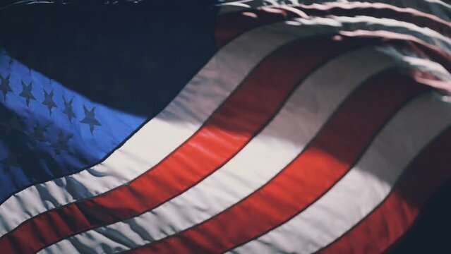 Close up slow motion 120fps the National Flag of the United States of America waving in the wind at night illuminated by street lamp. Symbol of Democracy and independence 