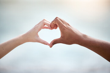 Interracial couple, beach and love with heart hands for valentines day, support or care together in...