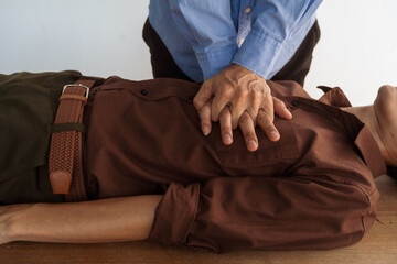 A focused view of a man demonstrating chest compressions on a CPR training class, illustrating hands-on learning in a classroom setting to master life-saving techniques for emergency response. - obrazy, fototapety, plakaty