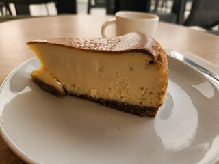 A slice of San Sebastian Cheesecake on a plate with a coffee in a cafe 