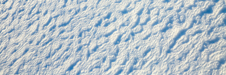 Beautiful winter background with snowy ground. Natural snow texture. Wind sculpted patterns on snow surface. Wide panoramic texture for background and design. - 794084895