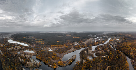 Autumn wide aerial panorama of Siverskyi Donets river valley with golden wooded riverbanks and grey cloudscape