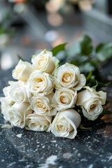 Bouquet of white roses laying on marble tombstone in cemetery. Funeral and mourning concept