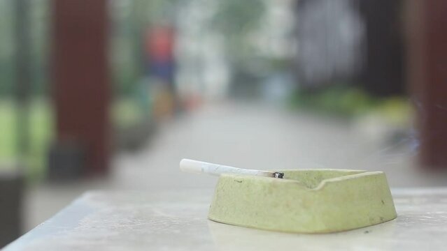 The cigarette is lit and stored in the ashtray