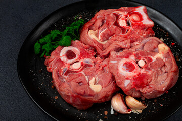 raw steak, calf's neck on the bone, fresh meat, on a black plate, top view, no people,