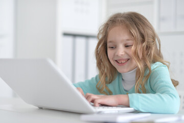 Cute and happy little girl children using laptop computer