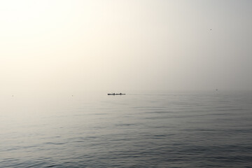 A serene vista captures two canoes gliding over Lake Garda placid waters, enveloped in the soft...