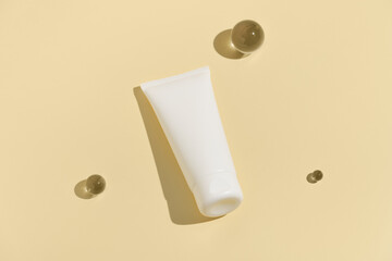 White face cream tube mockup and glass balls on yellow isolated background. Concept of beauty cosmetics, skin care, moisturizing and recovery. Image for your design.