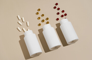 Three white mockup jars with scattered pills capsules diagonally on a beige isolated background. the concept of pharmacy, medical drugs and dietary supplements. Image for your design