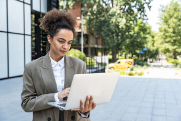 Portrait of young successful businesswoman office worker using laptop computer outside office...