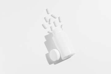 White mockup jar with scattered natural pills capsules diagonally on a white isolated background. Concept of pharmacy, dietary supplements, health care, drugs and antibiotics.