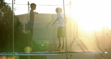 Children jumping inside trampoline outdoors