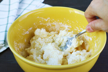 Hand mixing the mixture in a bowl with spoon for baking Brazilian cheese bread