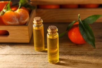 Bottles of tangerine essential oil on wooden table, closeup