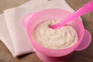 Baby food. Puree and spoon in bowl on wooden table