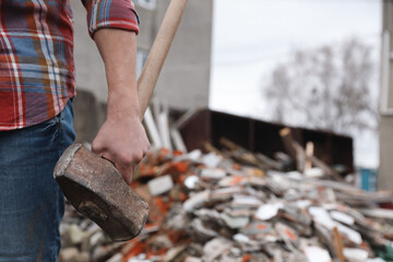 Man with sledgehammer near pile of broken stones outdoors, closeup. Space for text
